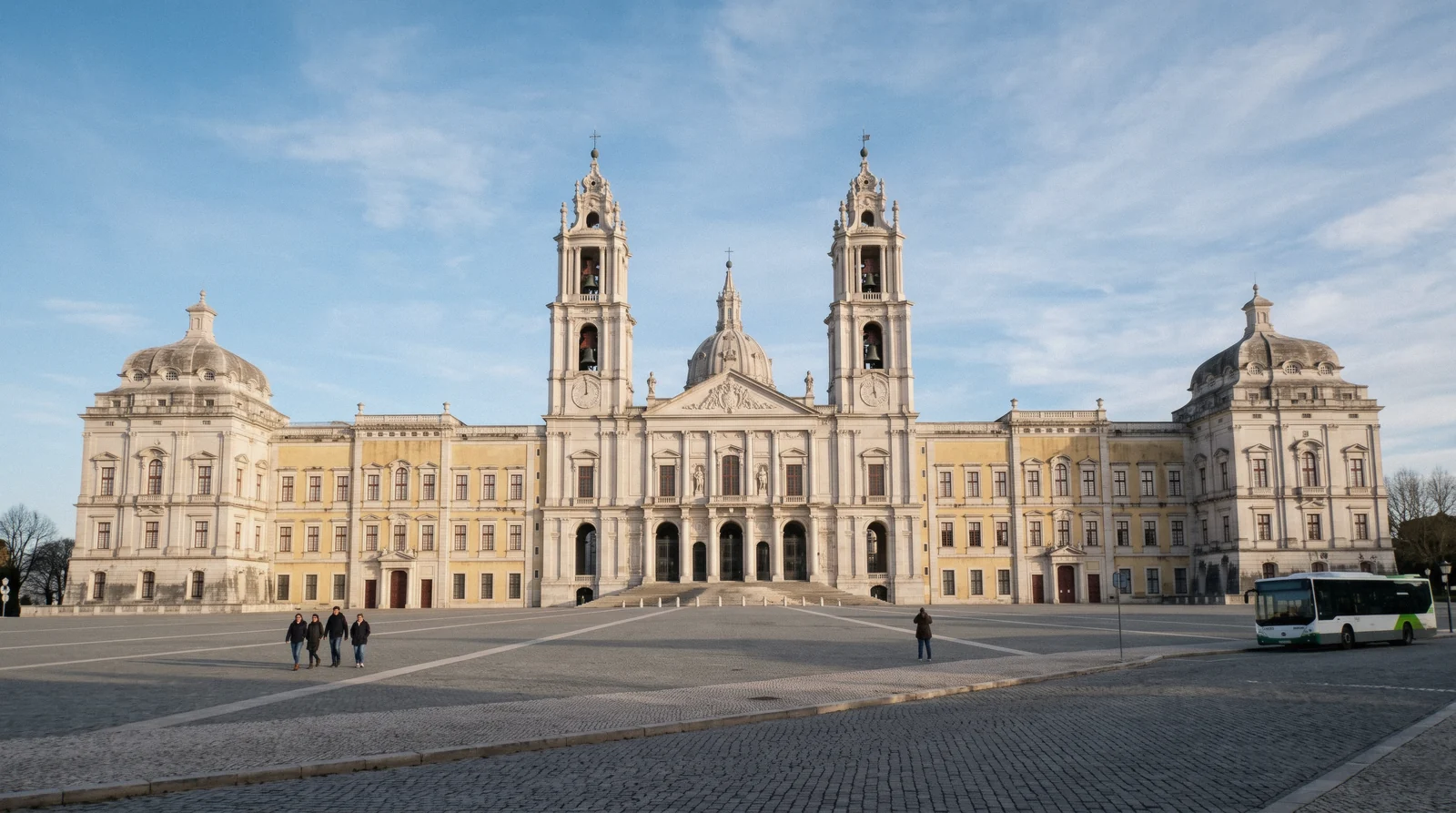 The long limestone facade and twin bell towers of Mafra Palace seen from Terreiro D. João V, a day trip from Sintra