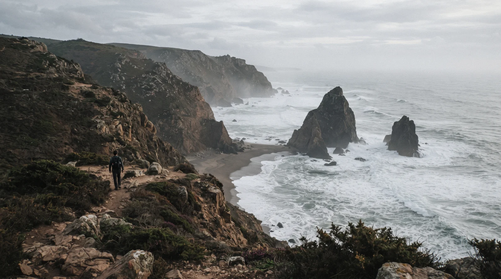 Sea stacks rising from the surf below steep cliffs at Praia da Ursa near Cabo da Roca, Sintra, Portugal